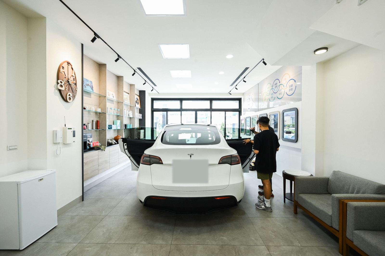白色特斯拉停在旭品門市內，四門打開準備貼隔熱紙