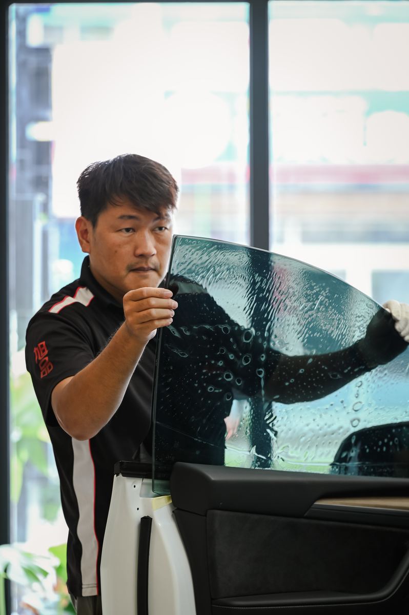 師傅拿起裁好的隔熱紙對準車門玻璃