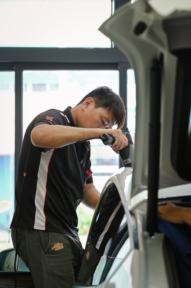 師傅對車門玻璃上的隔熱紙加熱定型